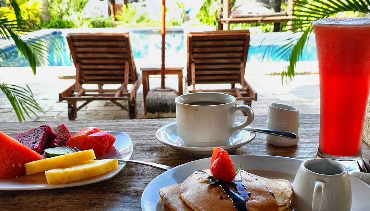 Breakfast with fruit, pancakes and coffee by the pool